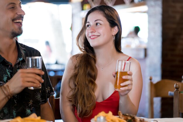 Jonge gelukkige paar genieten van tijd samen terwijl ze een date hebben in een restaurant.