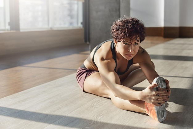 Jonge gemotiveerde vrouw die sportbeha-sneakers van activewear draagt in