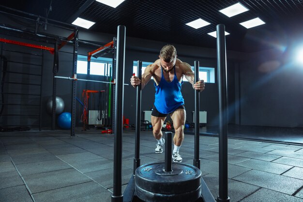 Jonge gespierde atleet training in de sportschool, krachtoefeningen doen