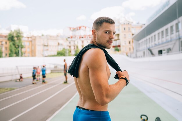 Jonge gespierde man Terugkijkend over zijn schouder. Portret van een knappe man blauwe korte broek.