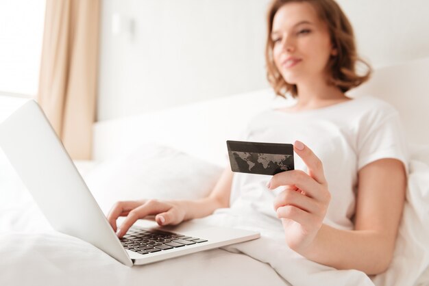 Jonge geweldige vrouw die laptop holdingscreditcard gebruiken