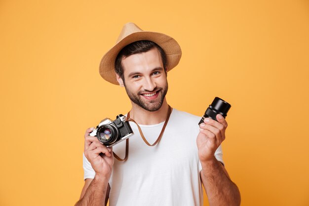 Jonge glimlachende mens die camera terwijl het houden van lens kijken