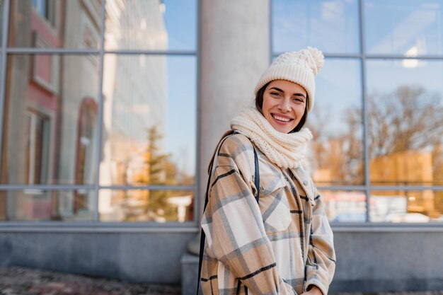 Jonge glimlachende vrouw die in de winter op straat loopt