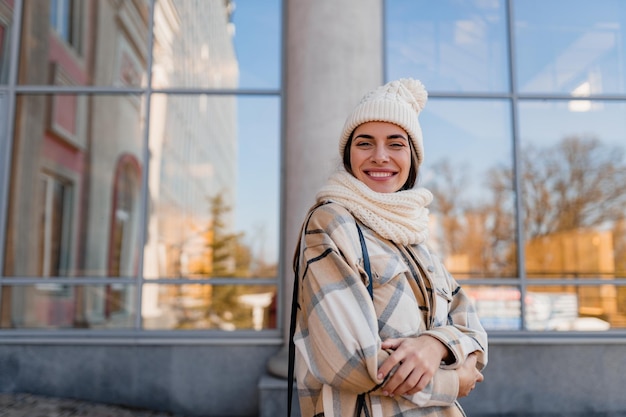 Jonge glimlachende vrouw die in de winter op straat loopt