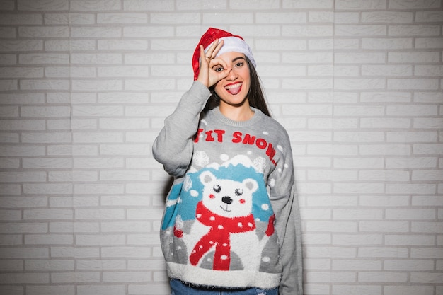 Jonge glimlachende vrouw in Kerstmishoed en sweater