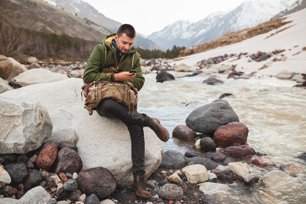 Jonge hipster man met smartphone, wilde natuur, wintervakantie, wandelen