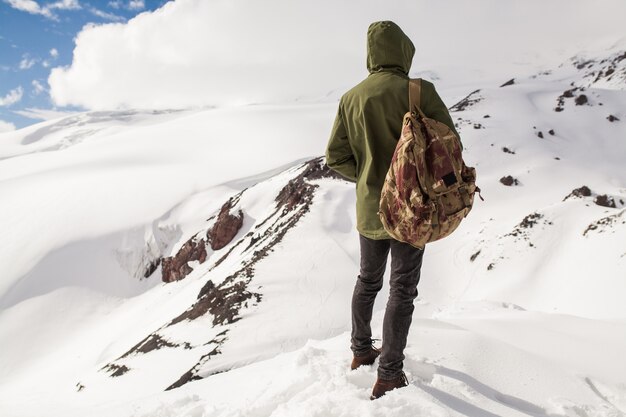 Jonge hipster man wandelen in de bergen, wintervakantie reizen