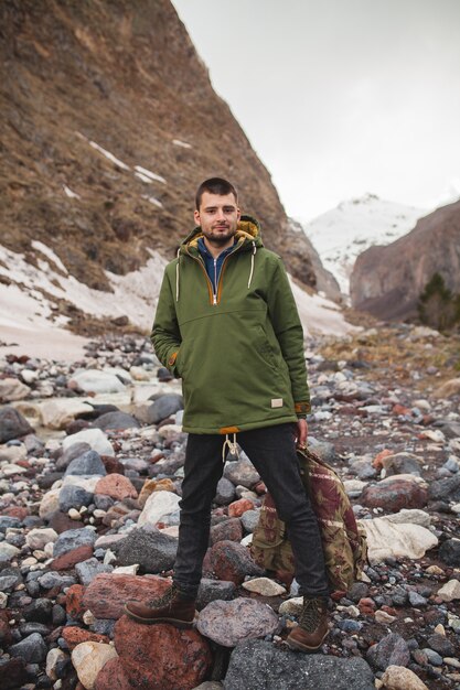 Jonge hipster man wandelen langs de rivier, wilde natuur, wintervakantie