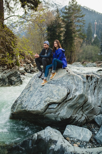 Jonge hipster mooie paar verliefd lopen op een rotsen aan de rivier in de winter woud