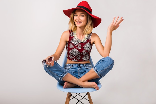 Gratis foto jonge hipster mooie vrouw zittend op een stoel geïsoleerd