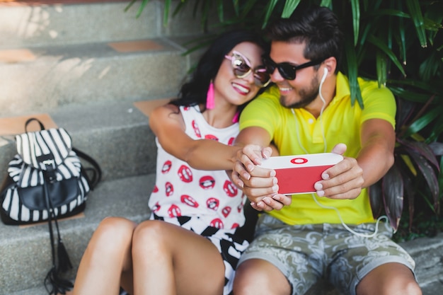 Jonge hipster verliefde paar, luisteren naar muziek op spreker, glimlachen gelukkig, plezier, zomer outfit, tropische vakantie, zonnebril