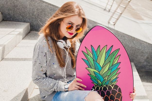 Jonge hipster vrouw in straat met balans bord trui en spijkerbroek dragen