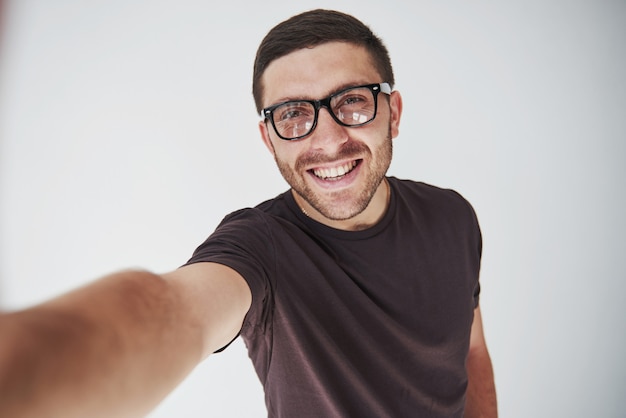 Jonge hipsterkerel die glazen dragen die gelukkig geïsoleerd op wit lachen