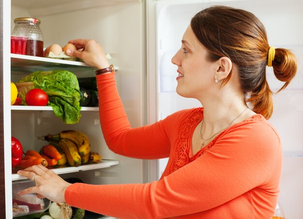 Jonge huisvrouw in de buurt van refrigerato