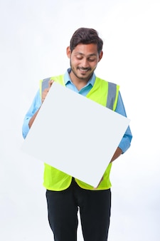 Jonge indiase bouwvakker weergegeven: leeg poster board op witte achtergrond.