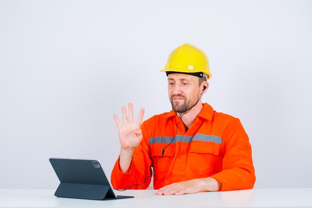 Jonge ingenieur toont nummer vier gebaar door voor zijn tablet op een witte achtergrond te zitten