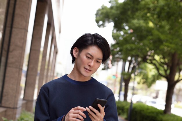 Jonge Japanse man in een blauwe trui buitenshuis