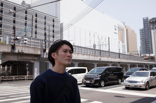 Jonge japanse man in een blauwe trui in de stad