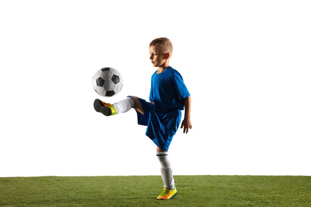 Jonge jongen als een voetbal of voetballer in sportkleding die een schijnbeweging of een schop met de bal voor een doel op wit maakt.