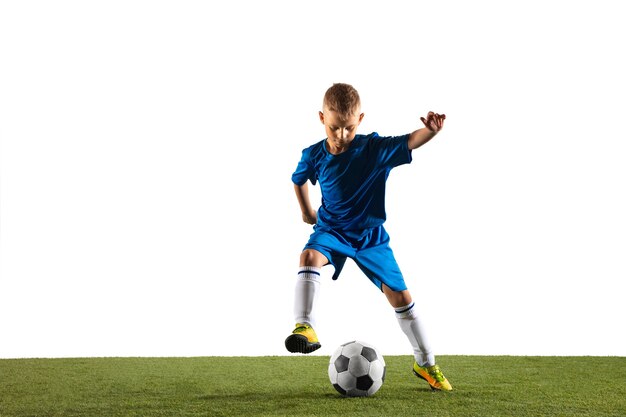 Jonge jongen als voetbal of voetballer in sportkleding die een schijnbeweging of een trap maakt met de bal voor een doel op een witte muur.