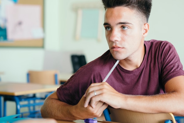 Jonge jongen denken met de potlood op zijn kin