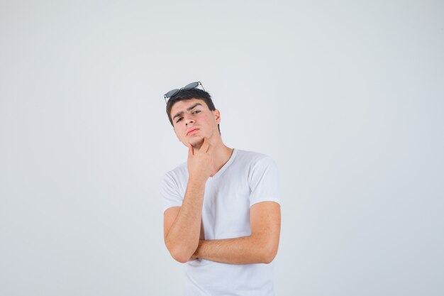 Jonge jongen in t-shirt poseren tijdens het kijken naar de camera en op zoek naar ernstige, vooraanzicht.