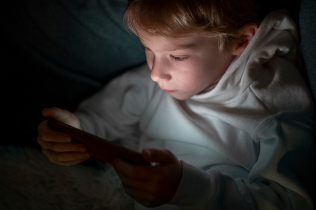 Jonge jongen met behulp van smartphone in bed