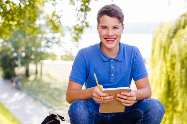 Jonge jongen met een notitieboekje in het park
