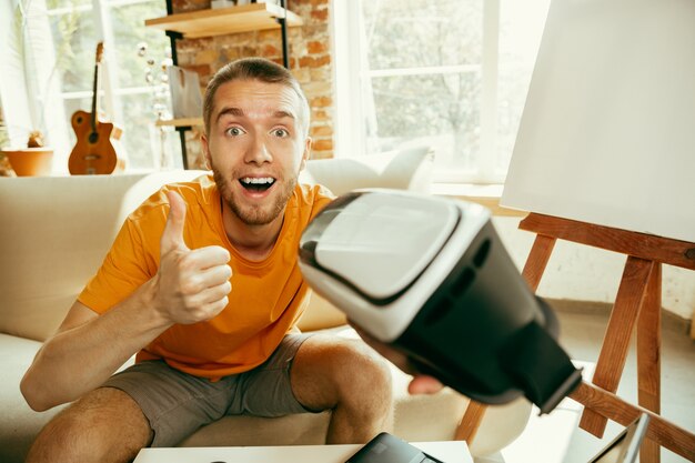 Jonge Kaukasische mannelijke blogger die met professionele apparatuur videoreview van Vr-bril thuis opnemen