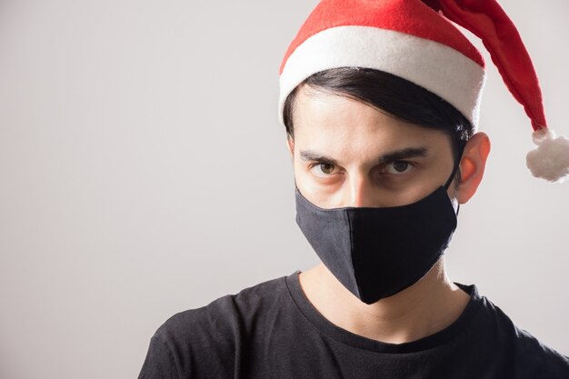 Jonge kerel die een Christmmas-hoed en een gezichtsmasker draagt