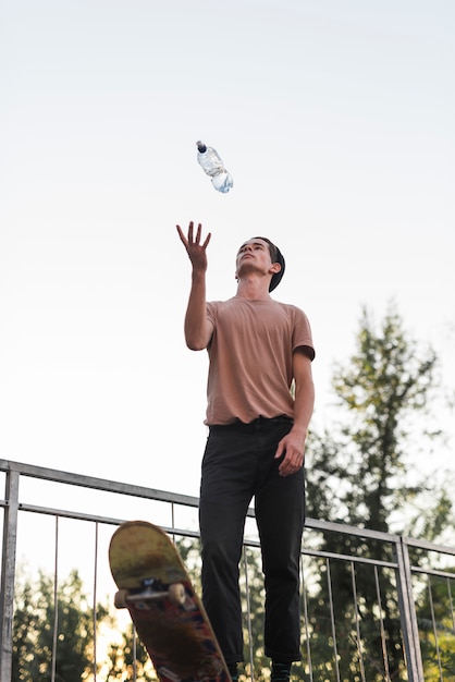 Jonge kerel poseren met skateboard en een fles water
