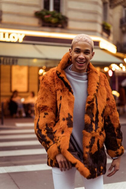 Jonge knappe Afro-Amerikaanse man poseren buiten in Parijs. gelukkige glimlach, mode-stijl. lichten van avondcafés.