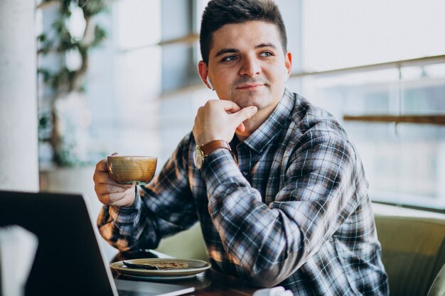 Jonge knappe bedrijfsmens die laptop in een koffie met behulp van