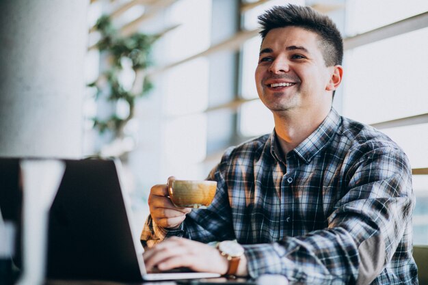 Jonge knappe bedrijfsmens die laptop in een koffie met behulp van