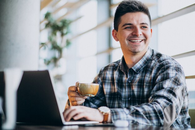 Jonge knappe bedrijfsmens die laptop in een koffie met behulp van