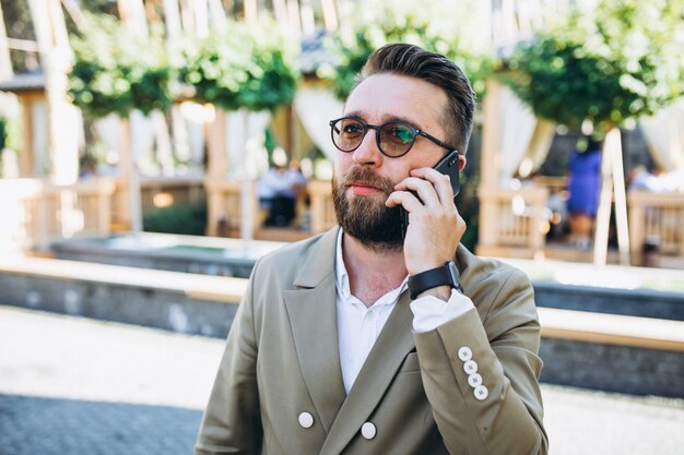 Jonge knappe bedrijfsmens die telefoon met behulp van