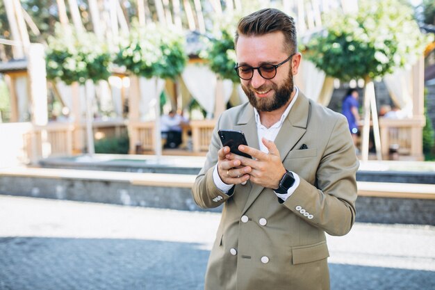 Jonge knappe bedrijfsmens die telefoon met behulp van