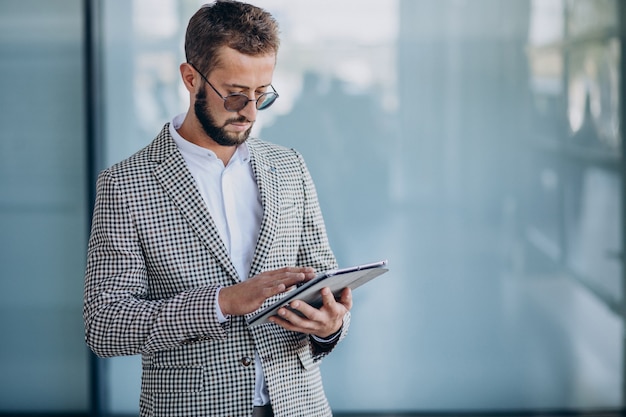 Jonge knappe bedrijfsmens in de tablet van de bureauholding