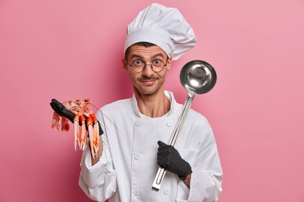 Jonge knappe chef-kok die ongekookte rivierkreeften geïsoleerd houdt