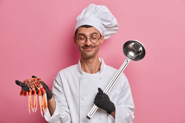 Jonge knappe chef-kok die ongekookte rivierkreeften geïsoleerd houdt
