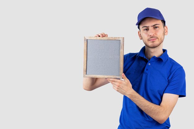 Jonge knappe jongen in bezorguniform met leeg frame