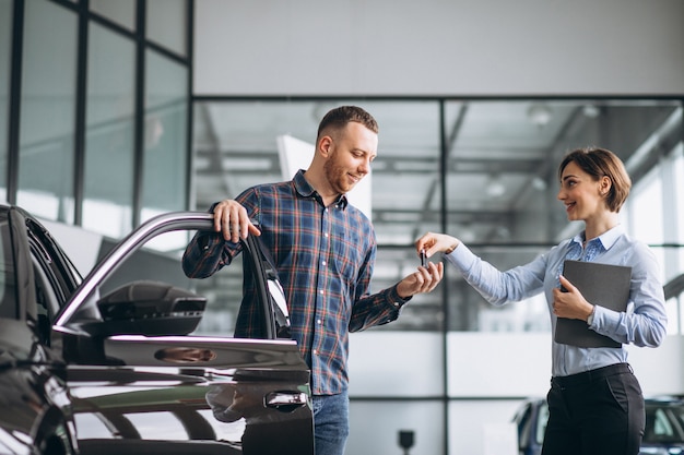 Jonge knappe man die een auto in een autotoonzaal kiest