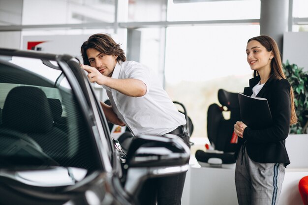 Jonge knappe man die een auto in een autotoonzaal kiest