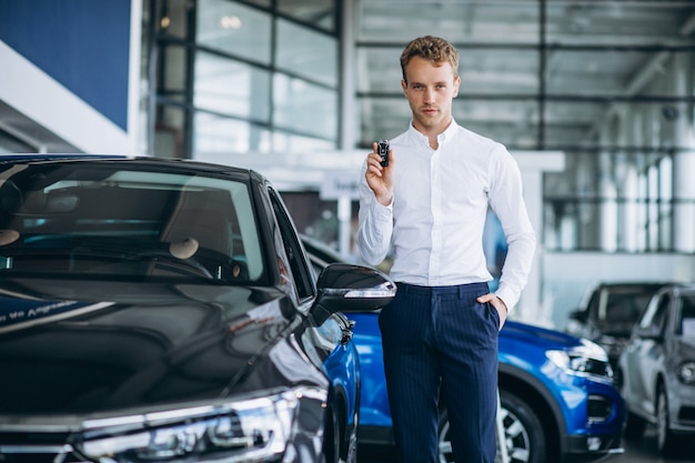 Jonge knappe man die een auto in een autotoonzaal kiest