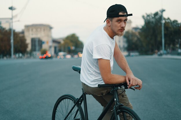 Jonge knappe man die zich voordeed tijdens het zitten op de fiets