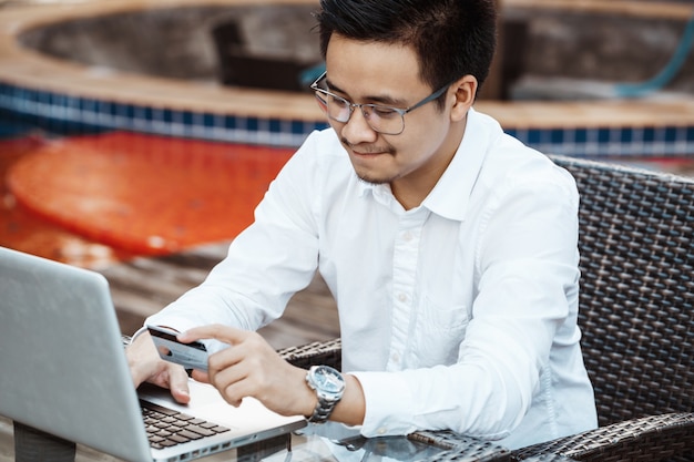 Jonge Knappe man geniet van online winkelen op mobiele telefoon met creditcard.