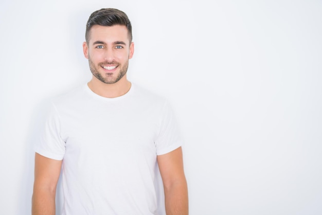 Jonge knappe man glimlachend blij casual wit t-shirt dragen over witte geïsoleerde achtergrond