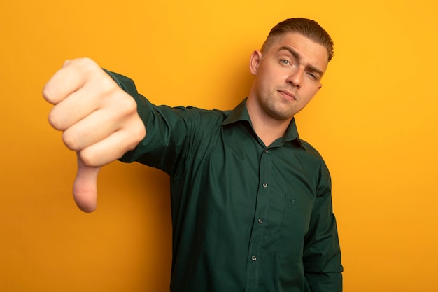 Gratis foto jonge knappe man in groen shirt ontevreden weergegeven: afkeer