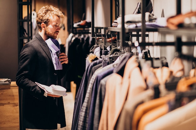 Jonge knappe man kiezen shirt in een winkel