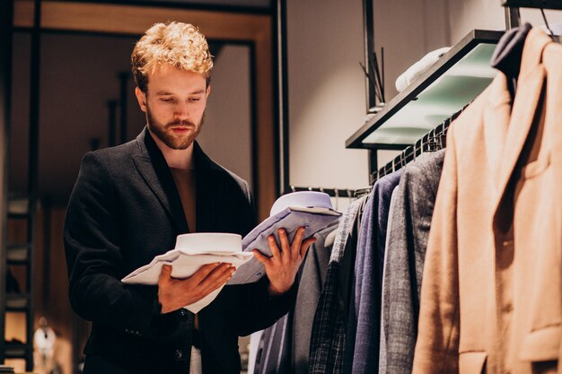 Jonge knappe man kiezen shirt in een winkel